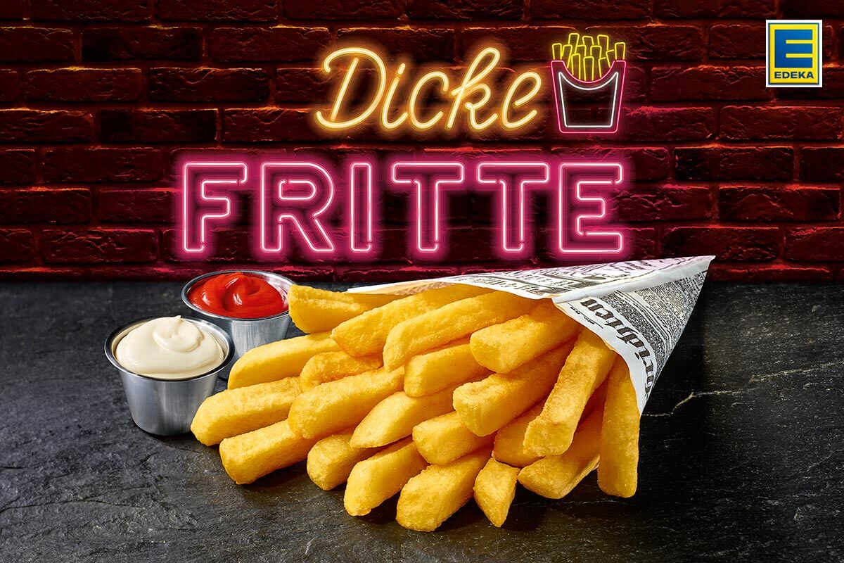Edeka: Papierzeitungstüte mit Pommes Frites auf Schieferplatte, daneben zwei kleine Gefäße mit Majo und Ketchup, dahinter in Leuchtbuchstaben: Dicke Fritte.