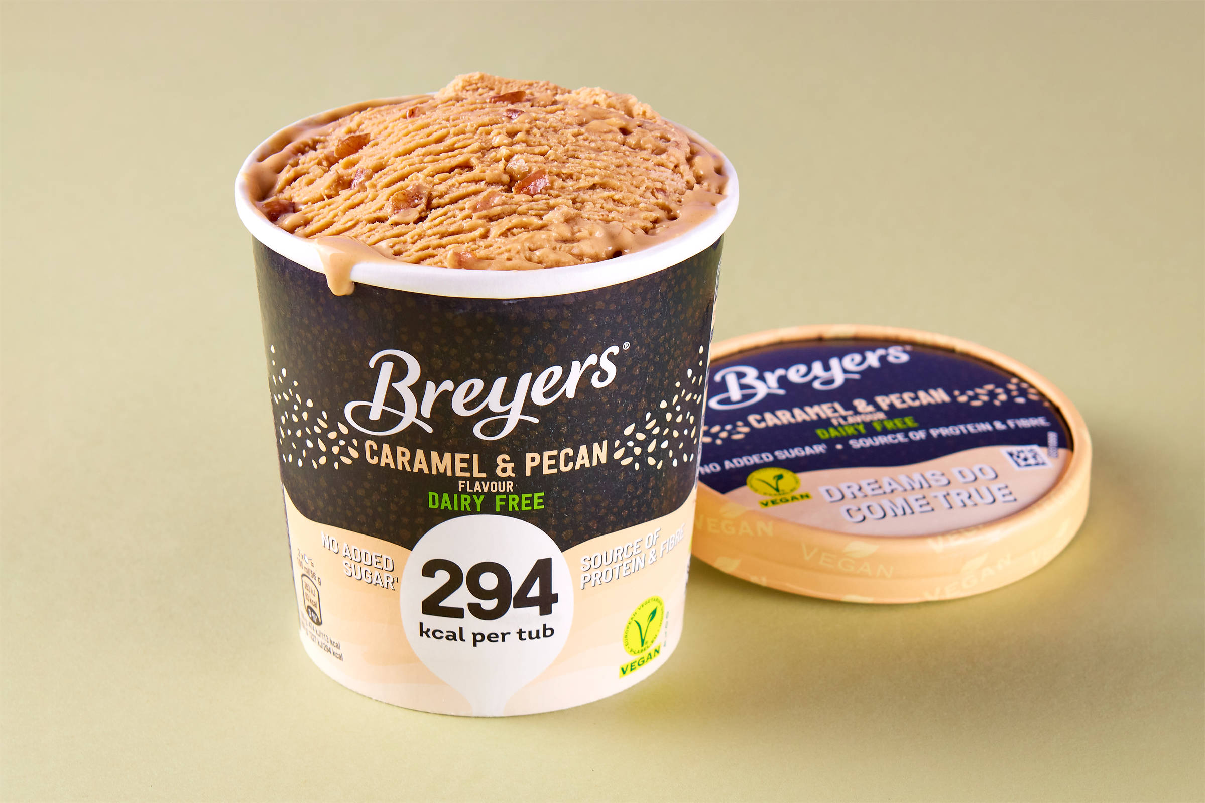Ein offener Behälter mit Breyers veganer Eiscreme Caramel & Pecan. Auf hellgrünem Untergrund.