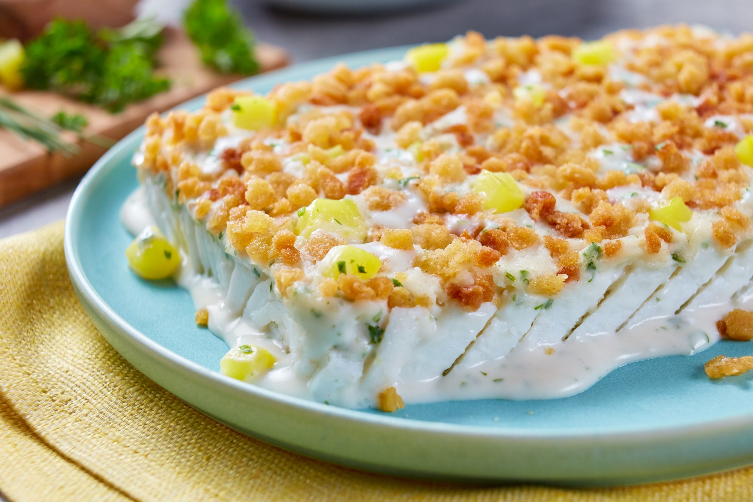 Frosta Schlemmerfilet Fischfilet auf hellblauem Teller auf gedecktem Tisch.
